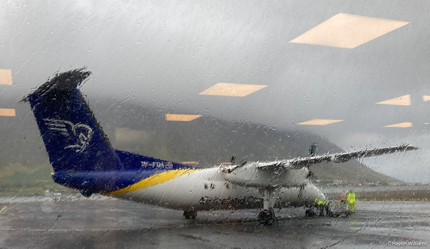 A propellor plane through a rainy window.