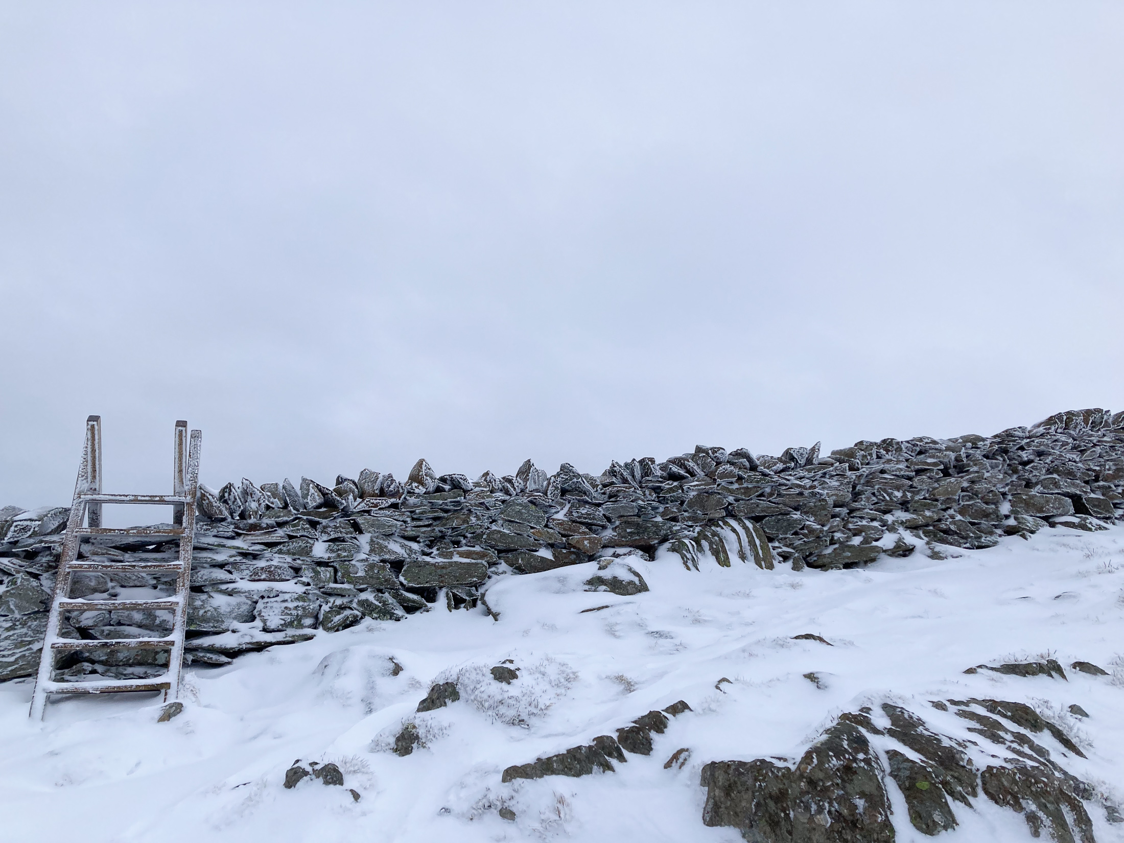 A stile over a snowy dry stone wall. © Haydn Williams 2025