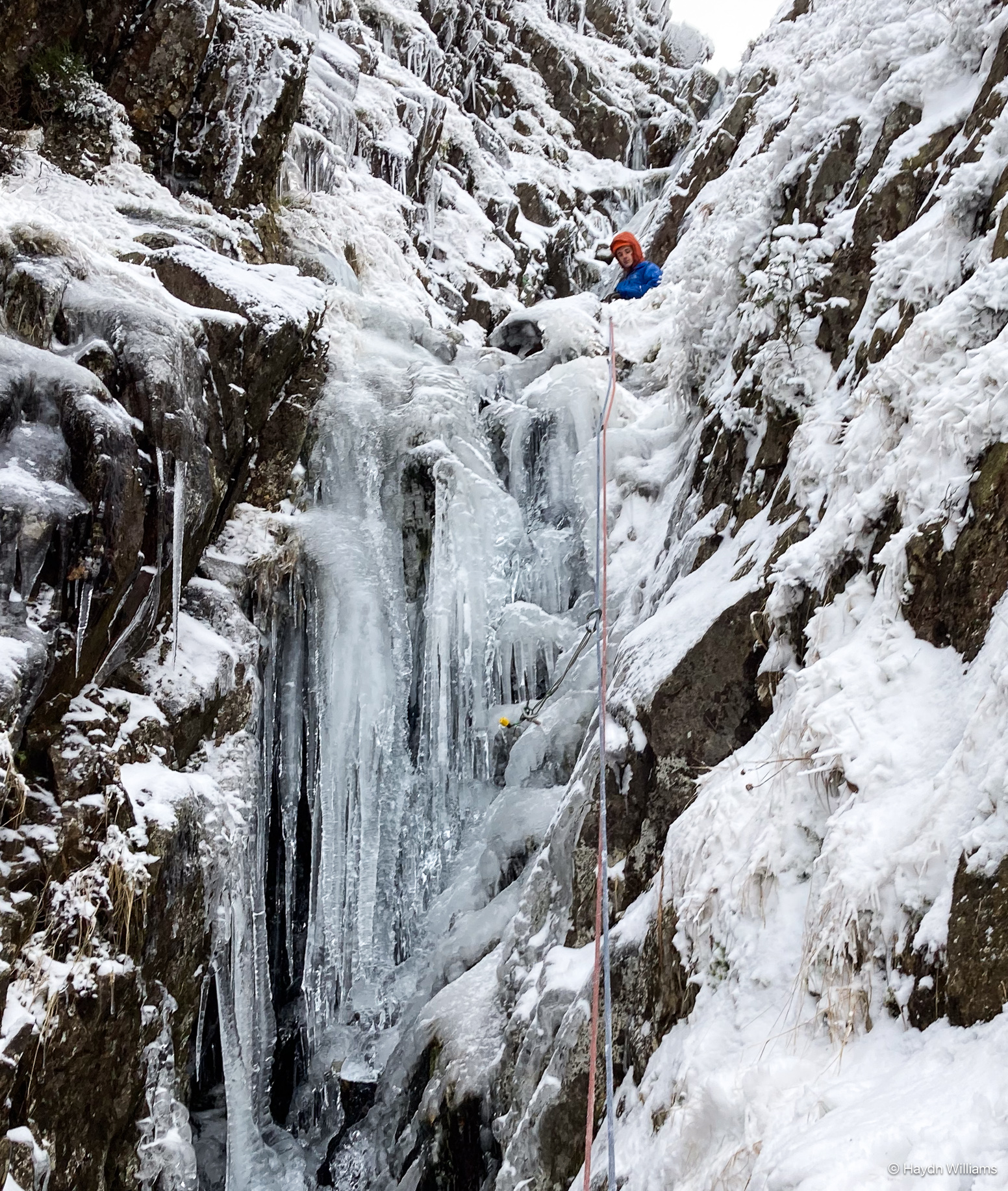 Frozen waterfall in a gully, with climbing ropes leading upwards. © Haydn Williams 2025